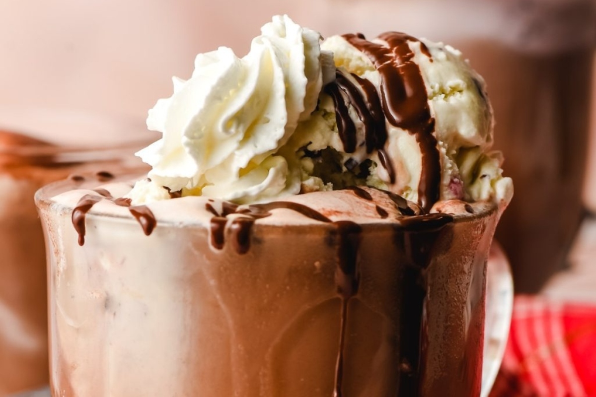 A cup of hot cocoa with whipped cream and ice cream.