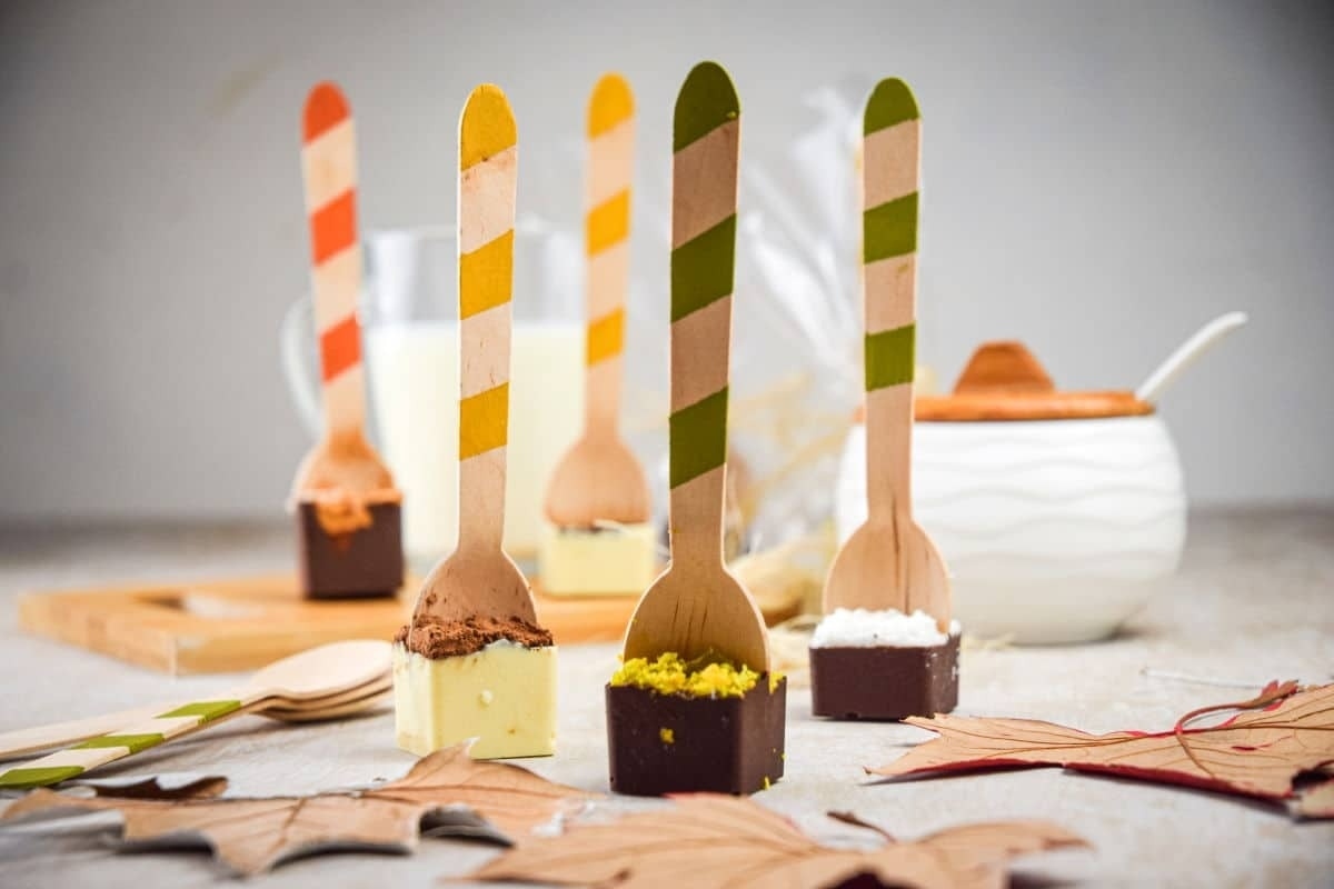 A group of wooden spoons with a variety of desserts on them, including cocoa/hot chocolate.