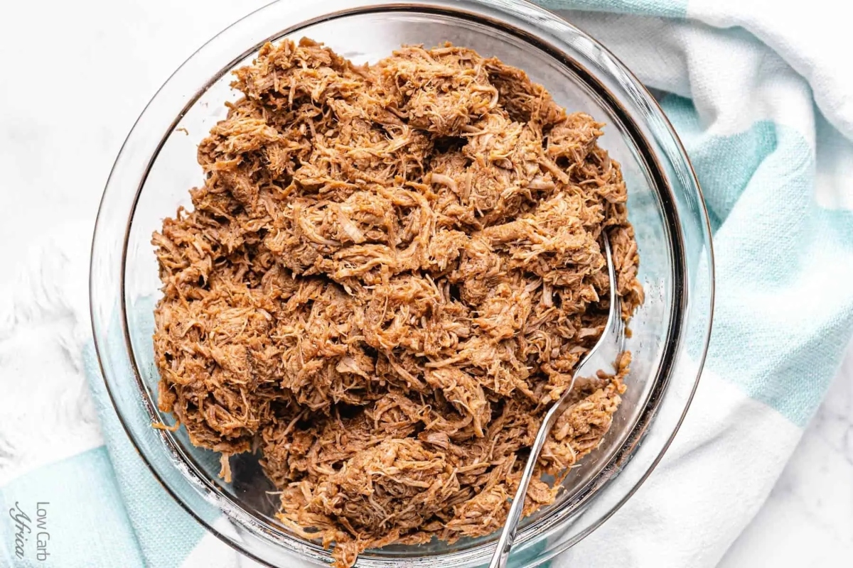 Delicious shredded pork in a glass bowl with a spoon.