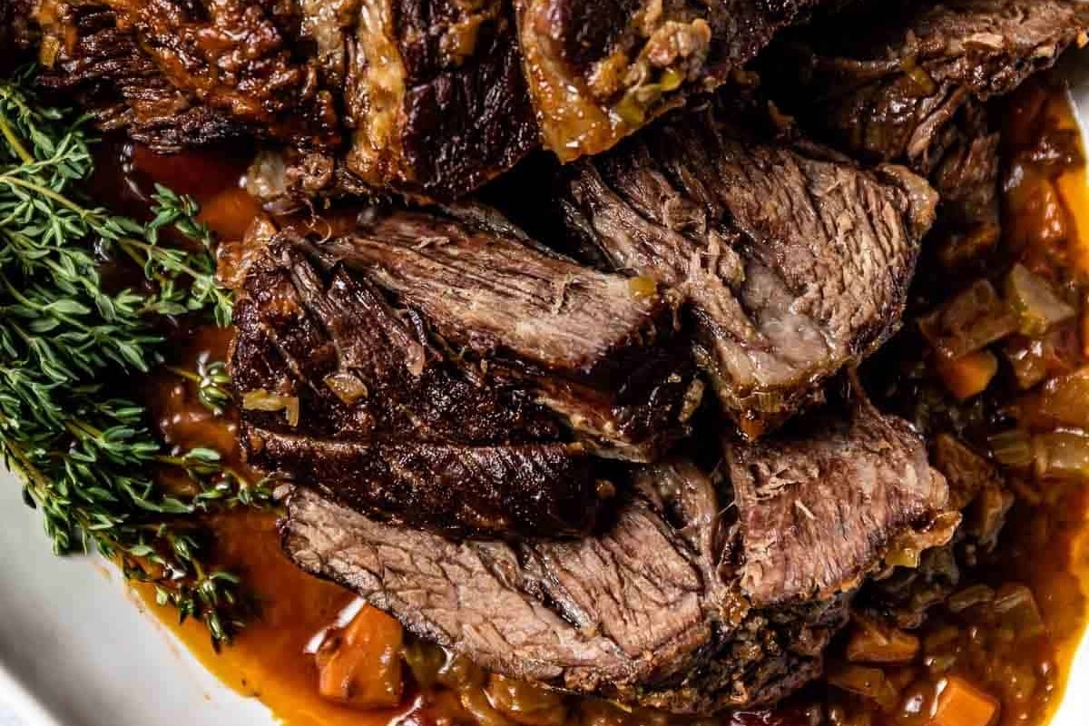 A plate of beef roast with sauce and sprigs of thyme, perfect for Christmas dinner.