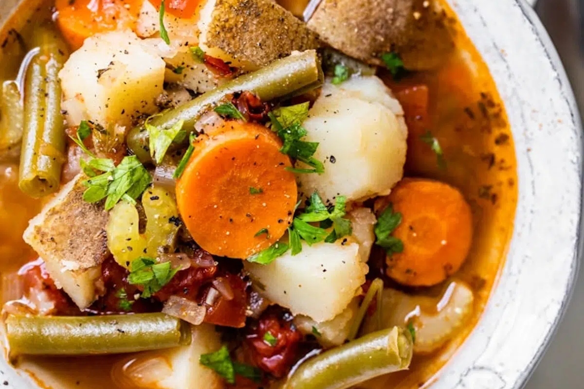 A bowl of vegetable stew with potatoes, carrots, and green beans.
