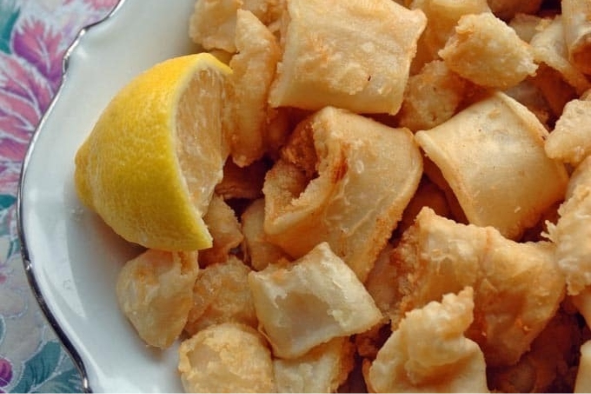 A succulent feast of fried octopus, perfectly plated on a white dish and accompanied by a tantalizing lemon wedge.