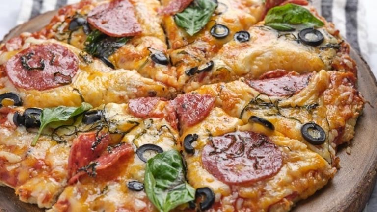 A low carb dinner option, this pizza features pepperoni and olives on a wooden plate.