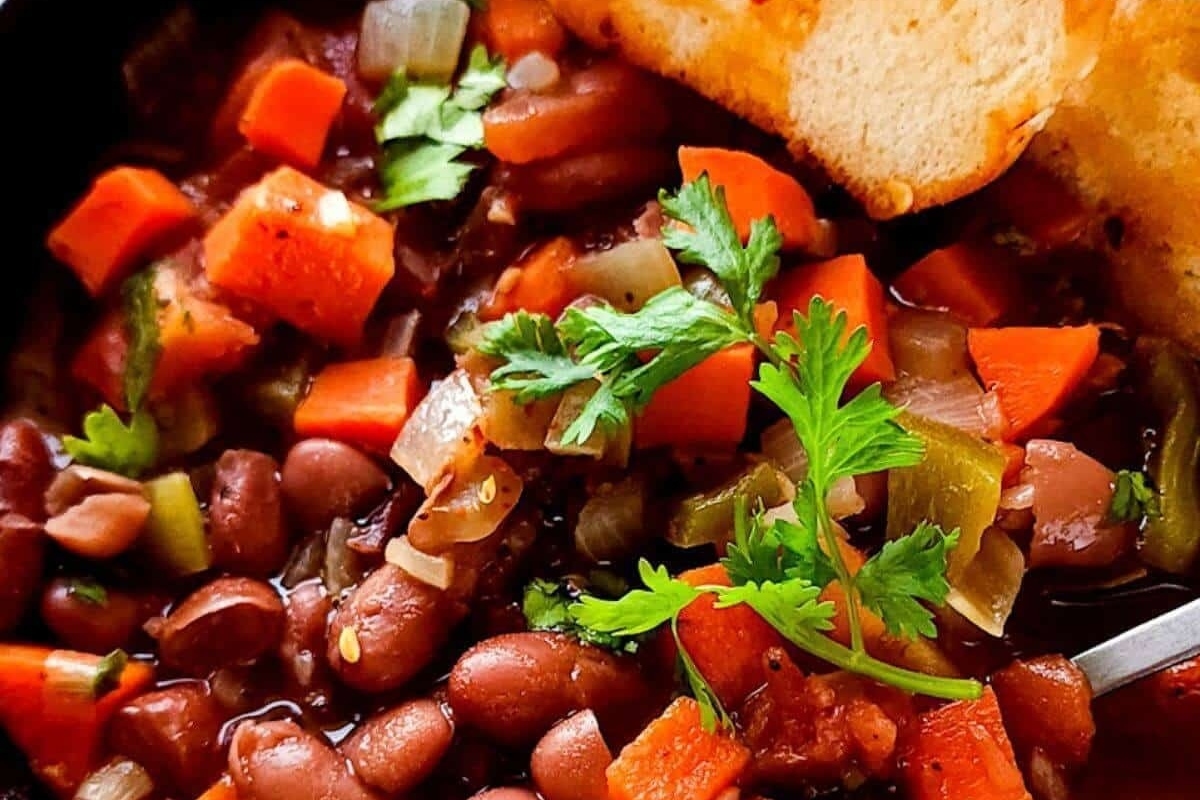 A hearty stew of bean and vegetable soup served with bread garnished with parsley.
