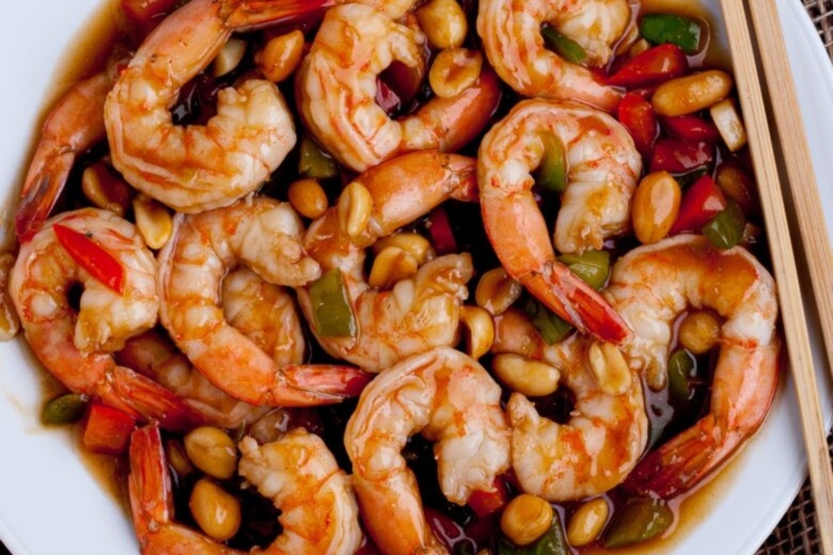 A white plate with shrimp and peanuts on it, perfect for shrimp dinners.