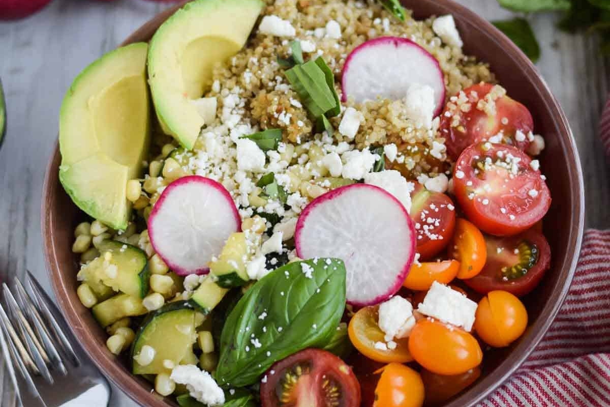 A Grain bowl of quinoa salad with radishes, tomatoes and avocado.