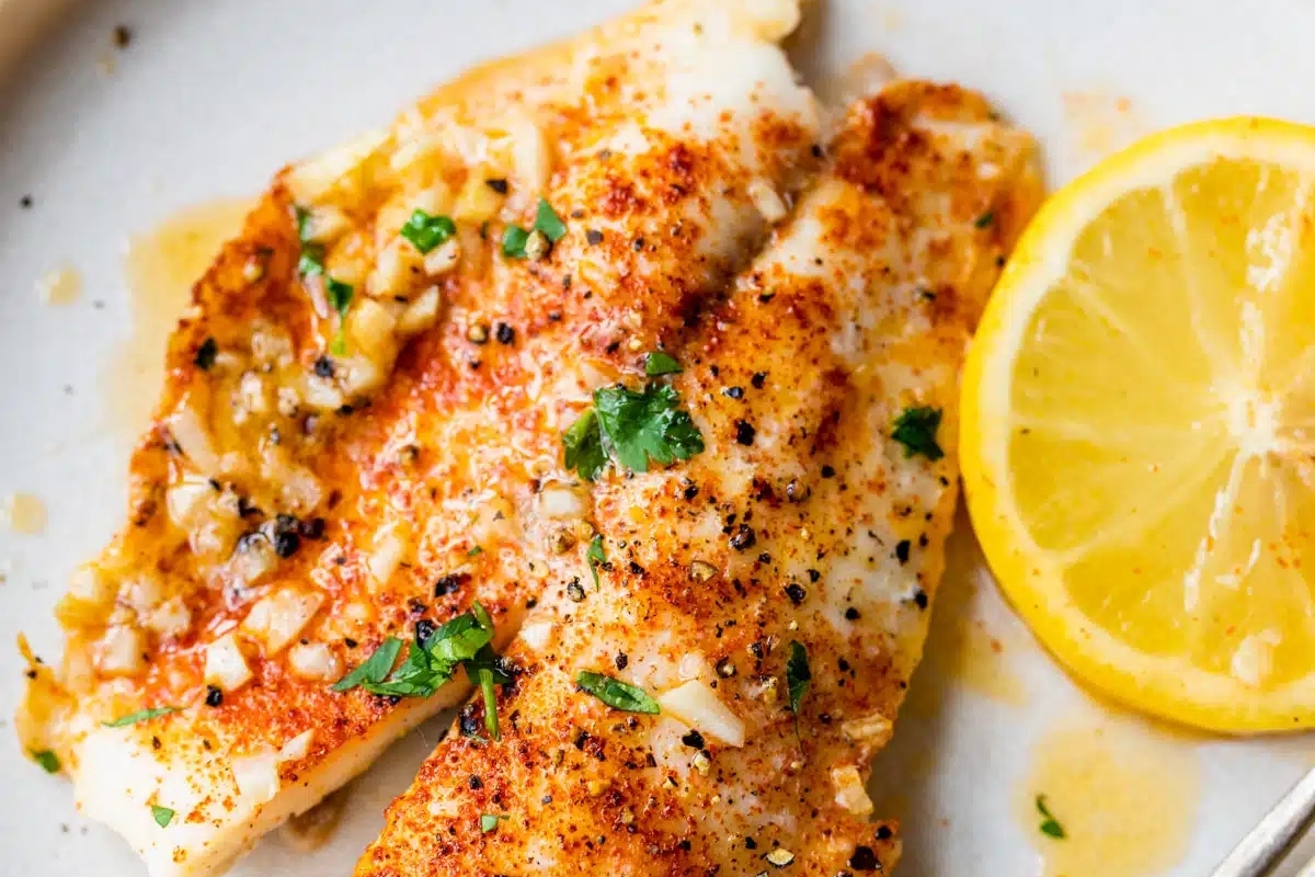 Fish fillets on a plate with lemon wedges. This recipe showcases the tantalizing flavors of fish, complemented by the zesty freshness of lemon.