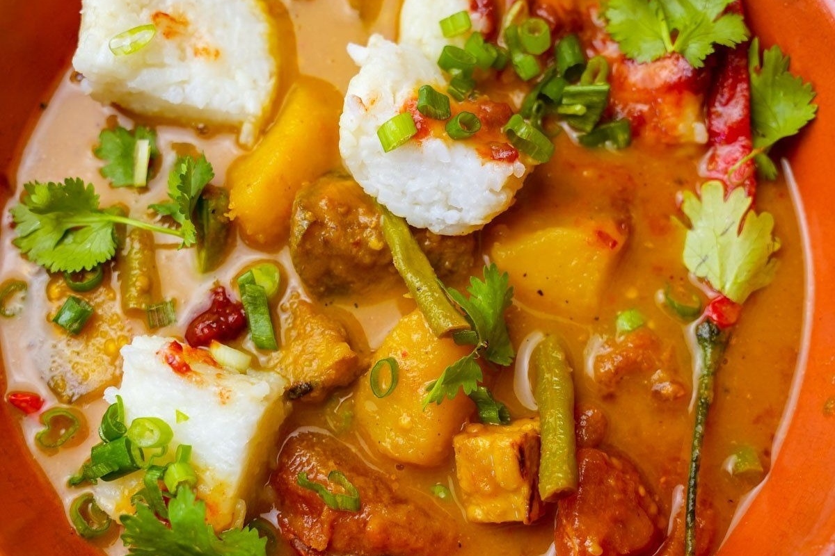 A steaming bowl of fish curry loaded with delicious vegetables.