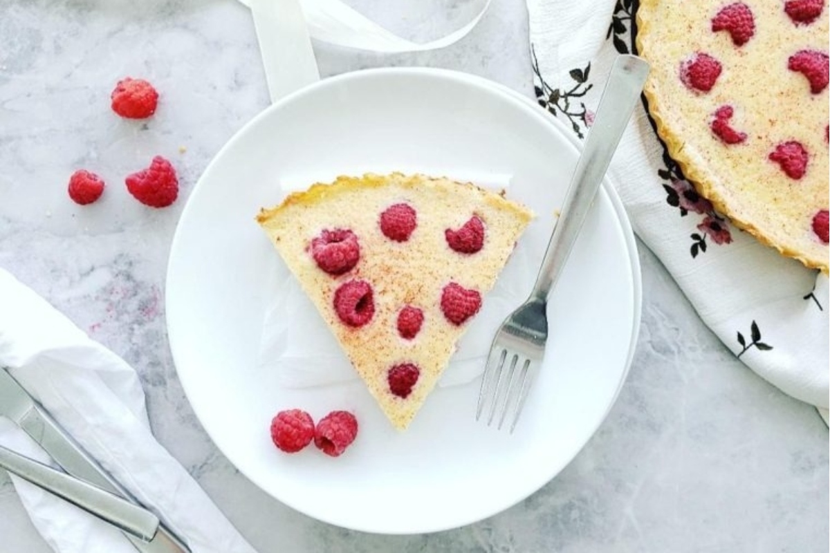 A delectable slice of raspberry tart, expertly crafted and presented on a plate with a fork.