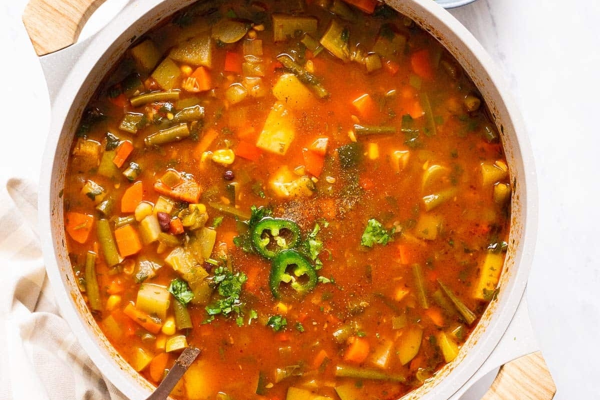 A delicious vegetable soup recipe served with a wooden spoon.