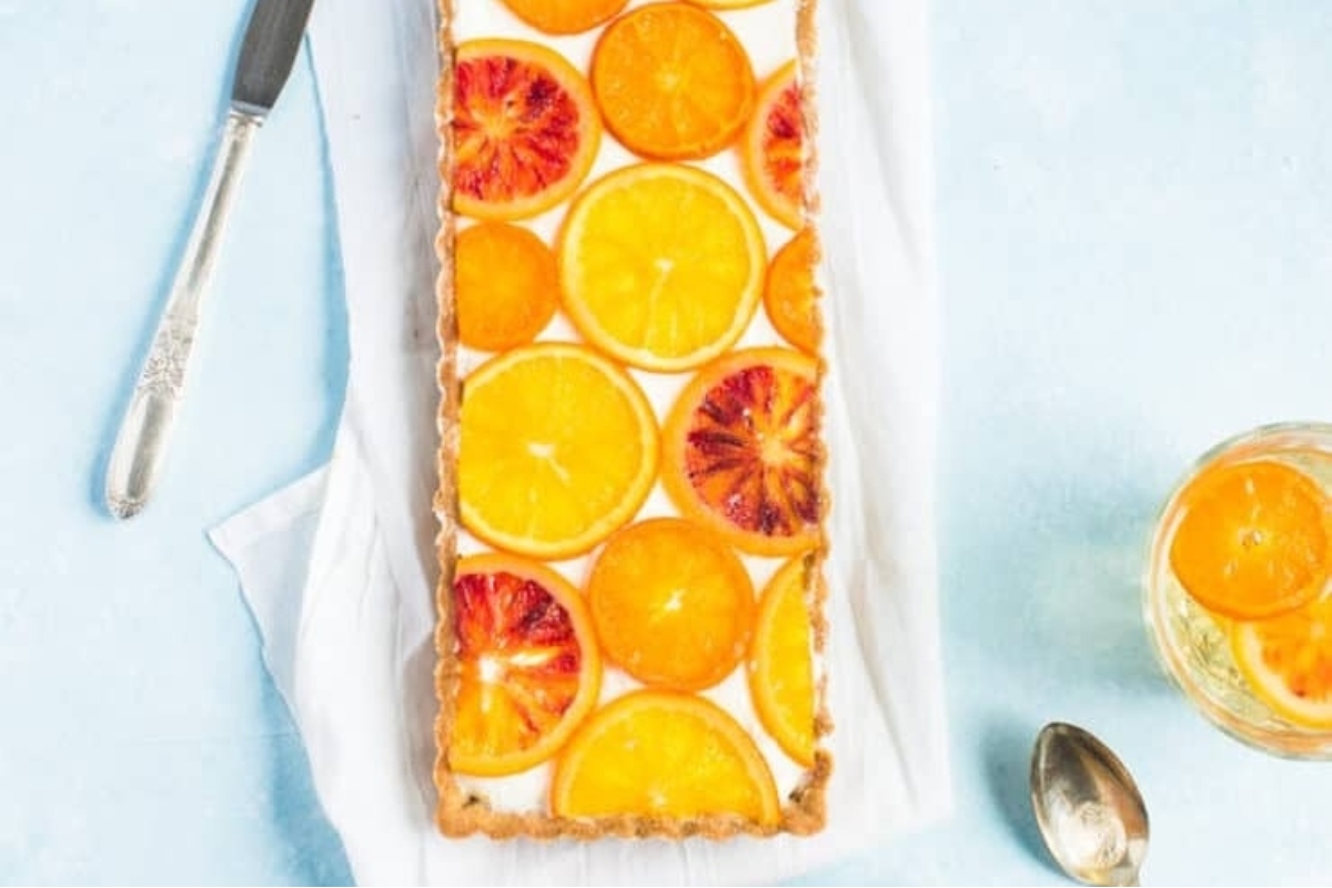 A delicious tart topped with fresh orange slices, beautifully presented on a rustic table.
