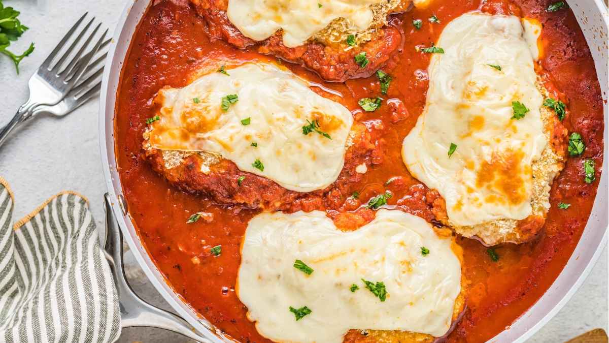 Mozzarella stuffed chicken parmesan in a pan.