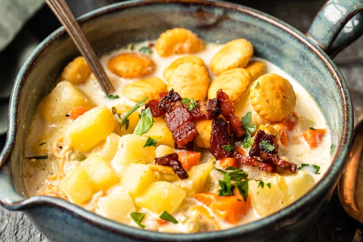 Chicken chowder soup in a blue bowl with potatoes and crackers.