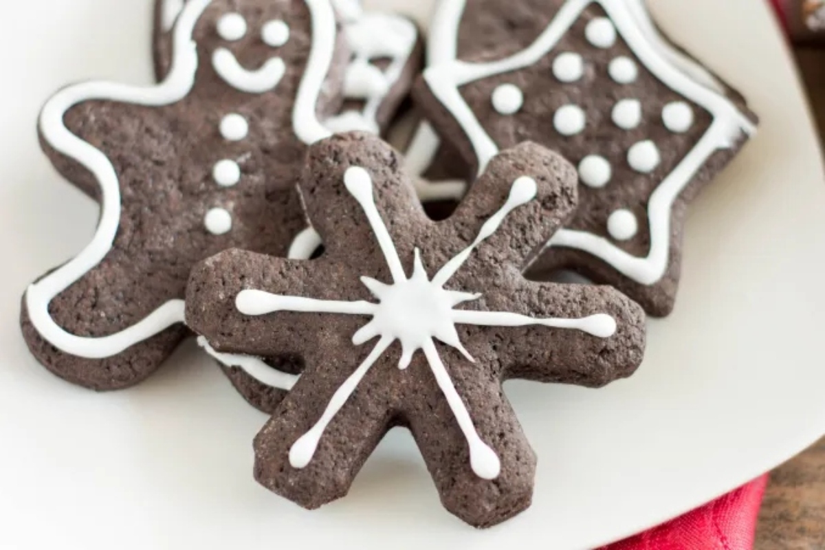 Delicious chocolate snowflake cookies with white icing displayed on a plate.