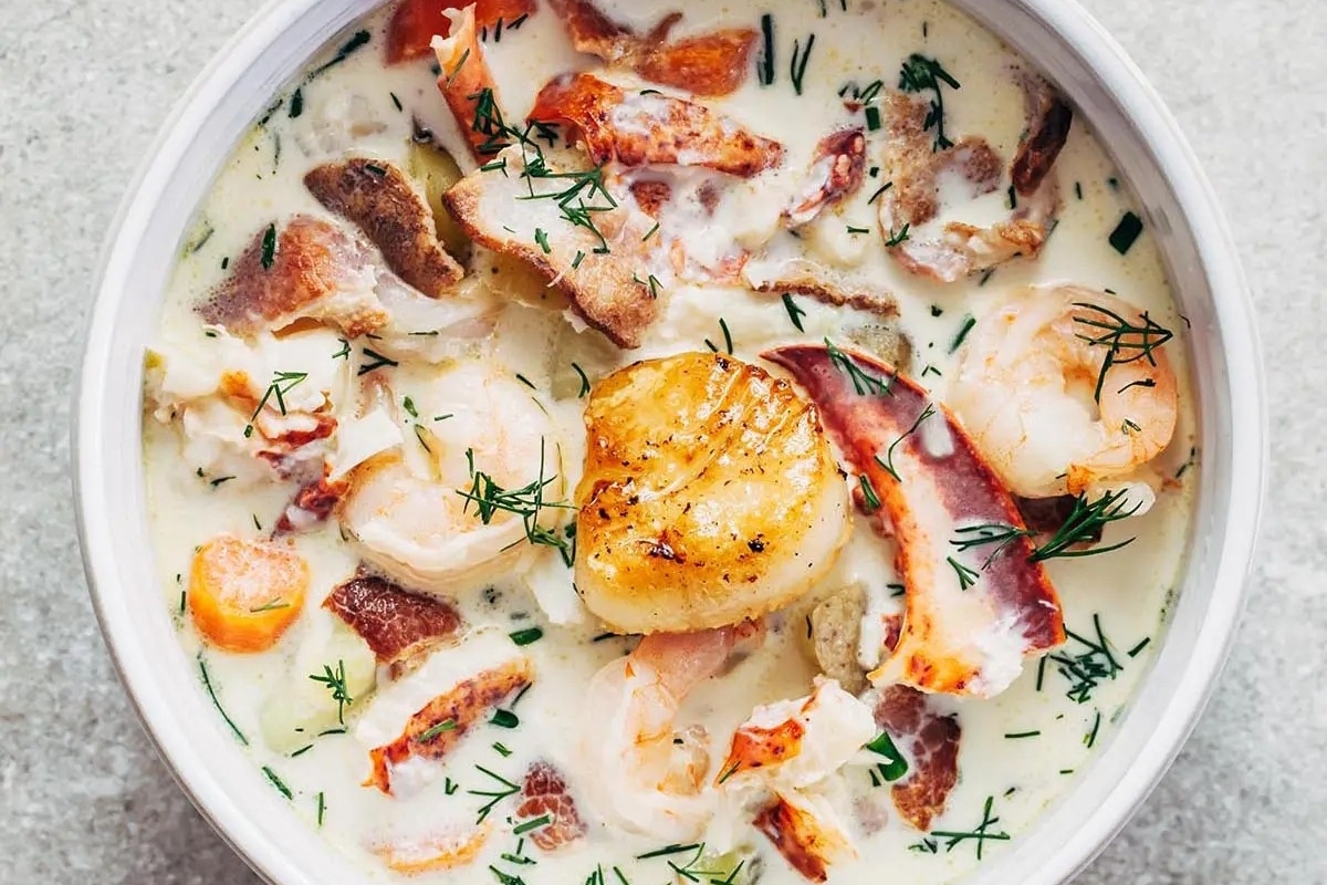 A bowl of surf chowder with bacon and dill.