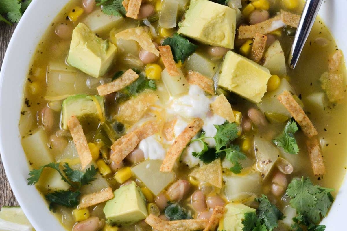 A bowl of Mexican potato soup with avocado and tortillas, perfect for chilly evenings.