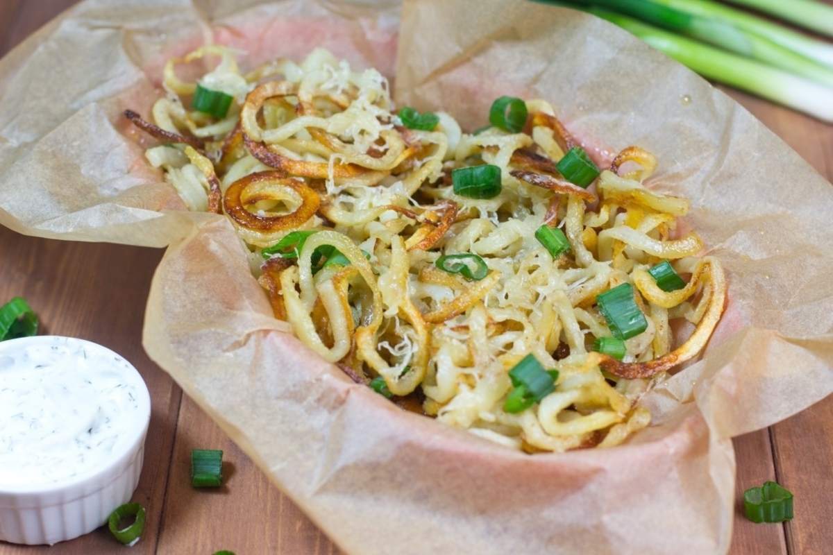 Onion rings made with a spiralizer, served in a paper bag with a dipping sauce.