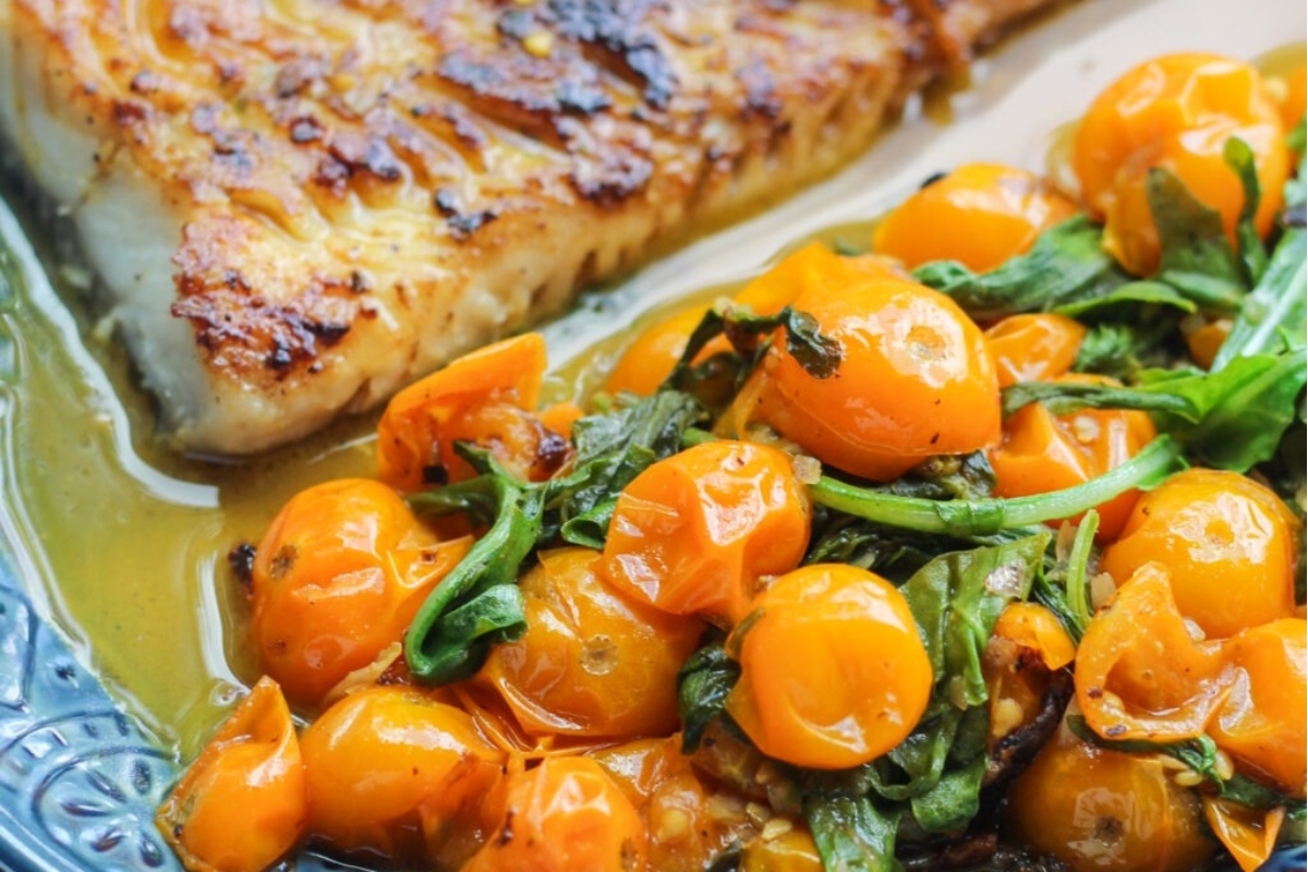A feast of fish and tomatoes on a blue plate.