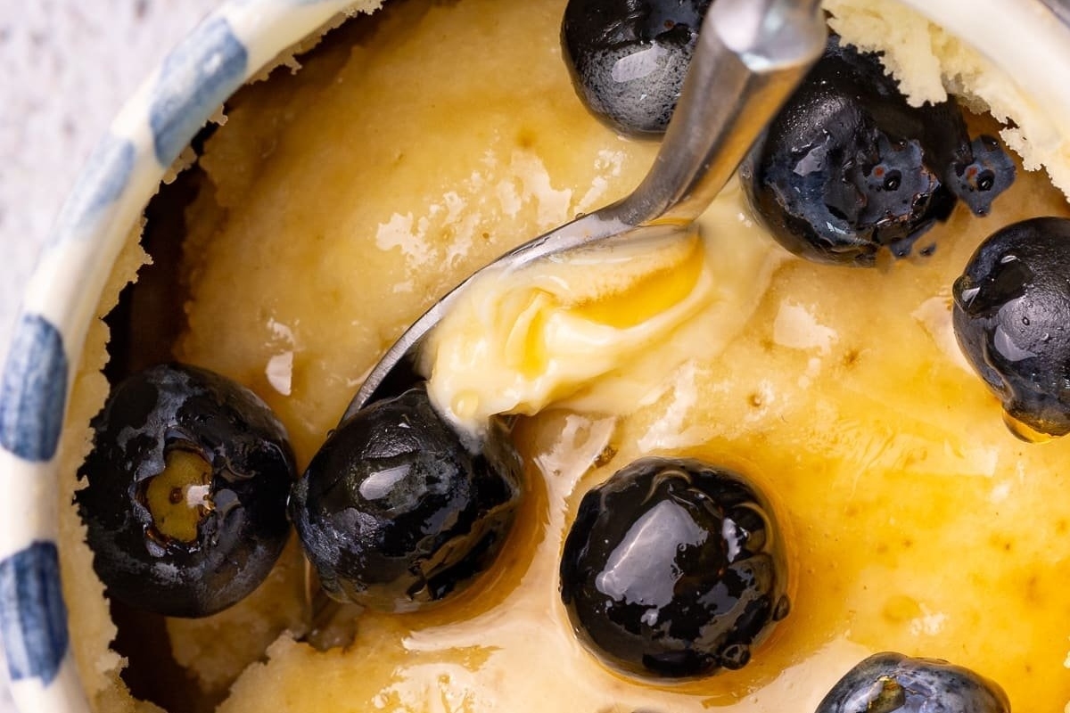A bowl with a spoon and blueberries in it, perfect for enjoying delicious mug cake recipes.