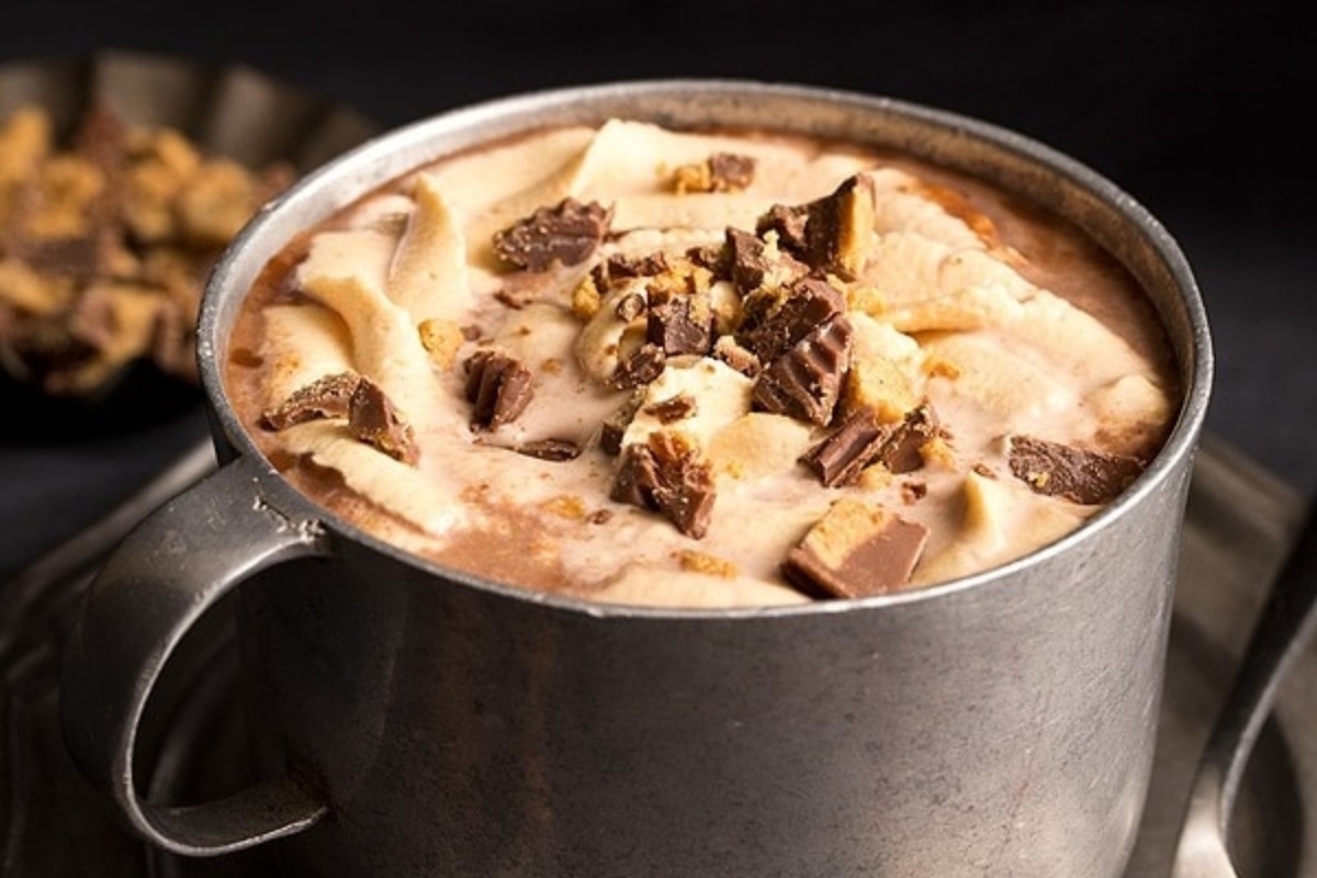 A steaming cup of cocoa topped with luscious chocolate and peanut butter drizzle.