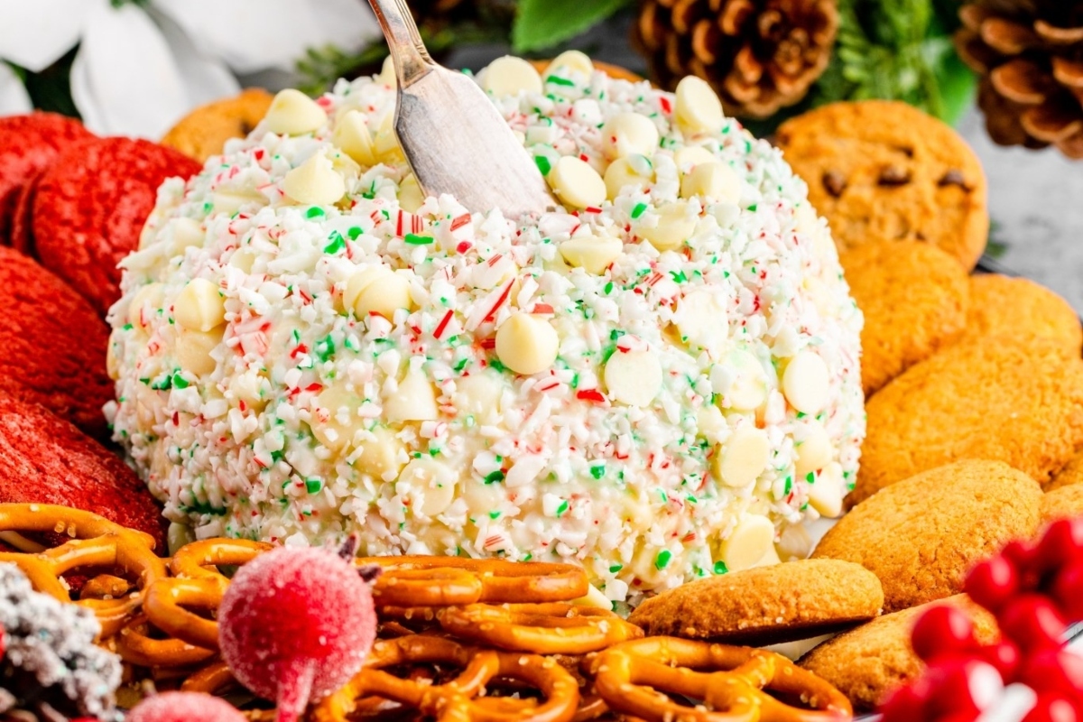 A festive cheese ball adorned with cookies and pretzels on a plate.