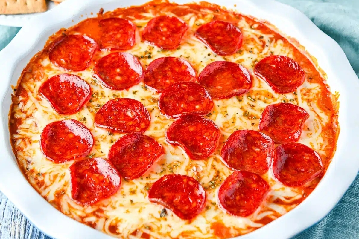 Cream cheese-based pepperoni dip served in a white dish with crackers.
