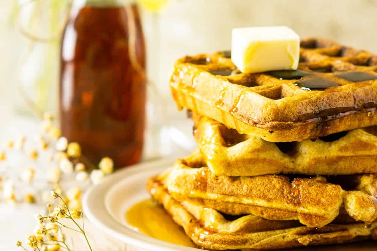 A plate of waffles topped with butter and syrup, made using delicious waffle recipes.