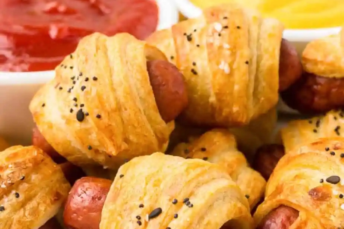 Bite-sized hot dogs wrapped in pastry with ketchup, perfect for Game Day.