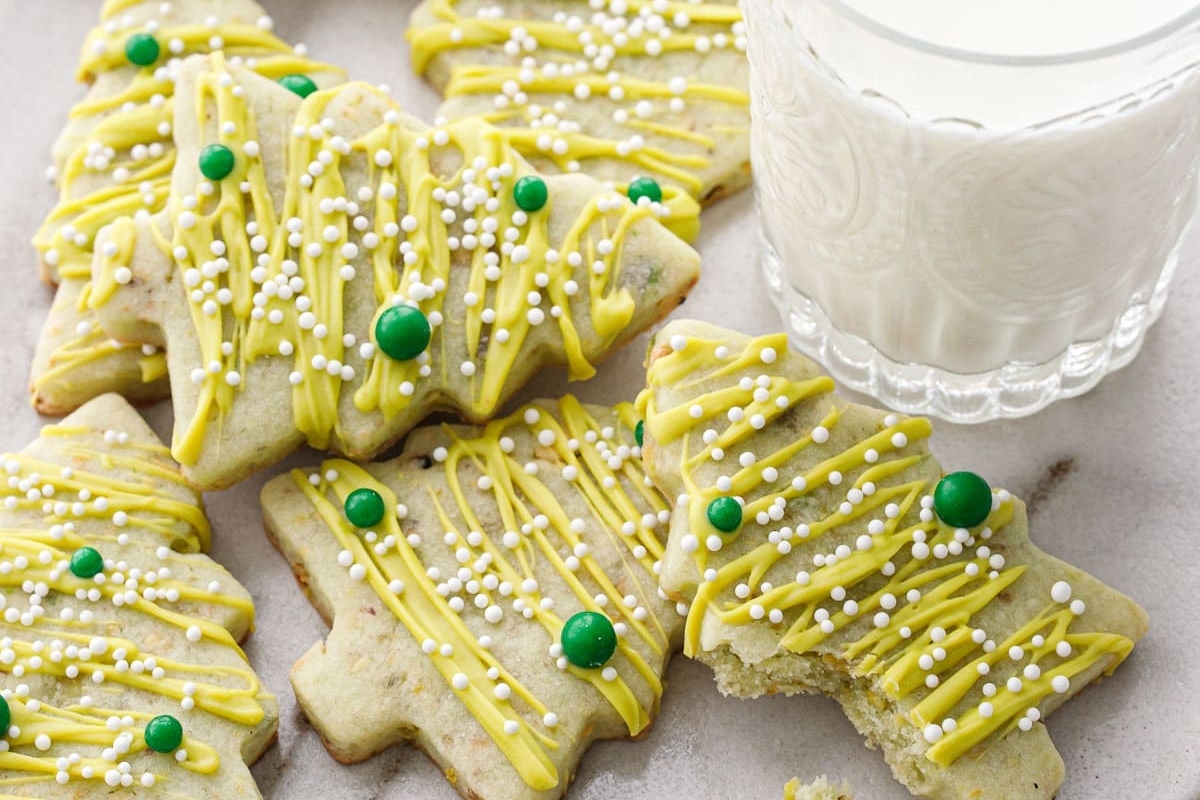 A plate of cookies with green sprinkles and a glass of milk, perfect for Christmas desserts.