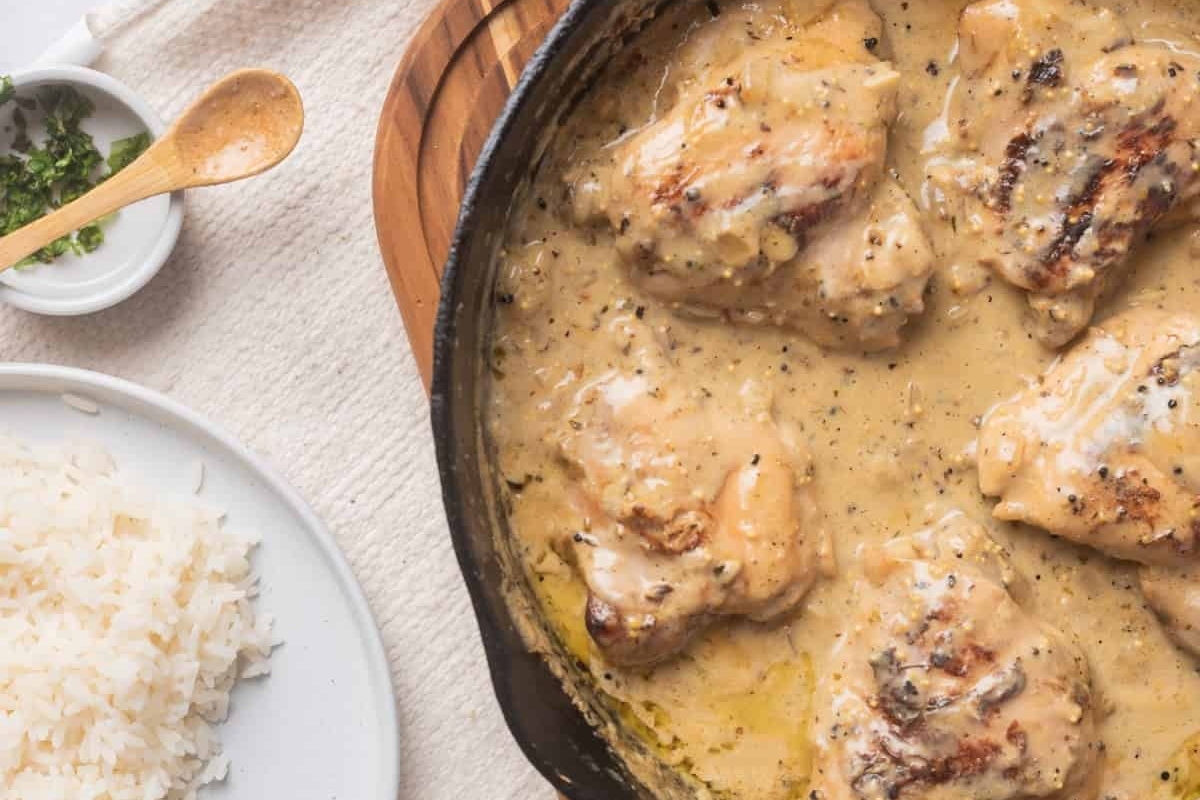 Chicken thighs in a skillet with sauce.