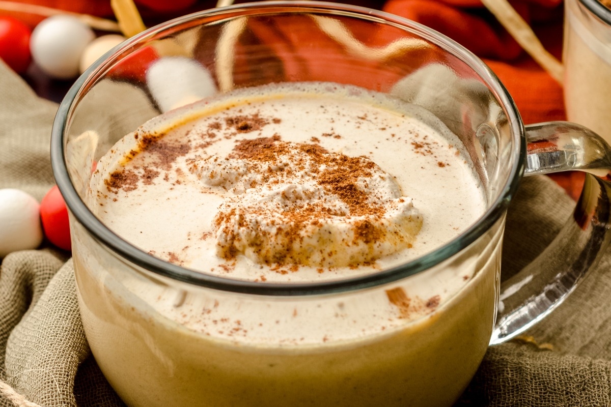 Two mugs of hot chocolate with whipped cream and cinnamon.