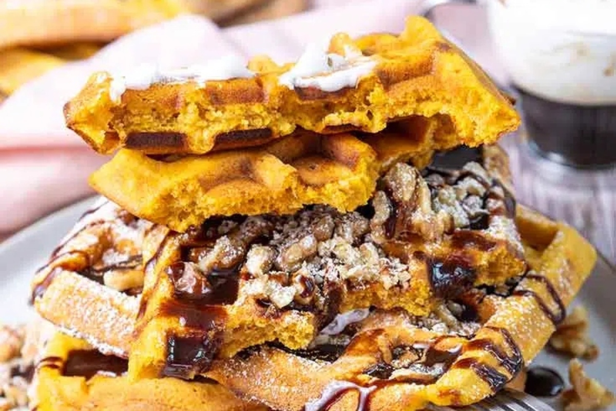 A stack of pumpkin waffles, bejeweled with autumn spices, on a plate.