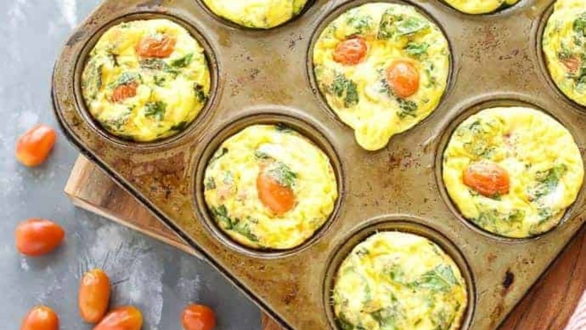 A healthy breakfast of high protein egg muffins, filled with spinach and tomatoes, baked in a muffin tin.