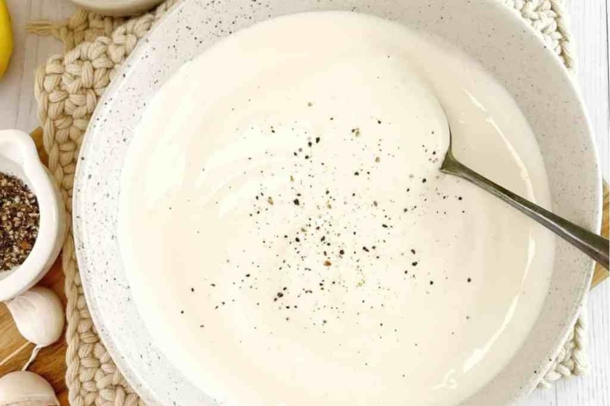 A bowl of soup with truffle oil drizzled over it, with a spoon next to it.