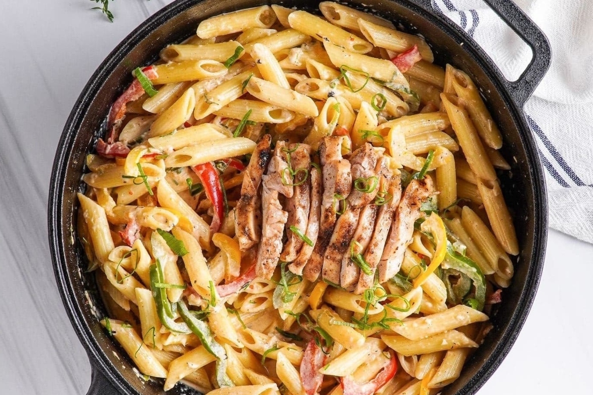 An inexpensive family dinner, filled with love, featuring a skillet full of pasta with chicken and vegetables.
