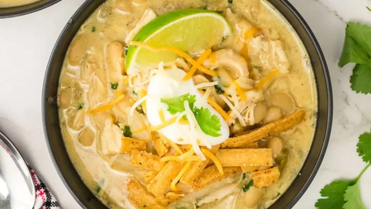 Chicken enchilada soup in a bowl with lime wedges.
