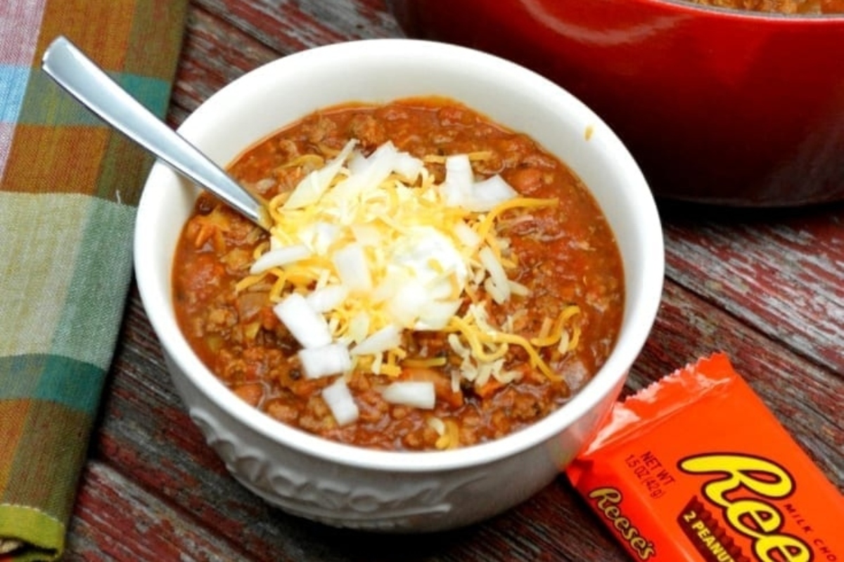 A mouthwatering bowl of chili served alongside a tempting bag of Reese's peanut butter cups.