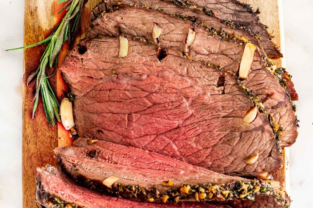 Christmas dinner - Beef tenderloin sliced on a cutting board with rosemary sprigs.