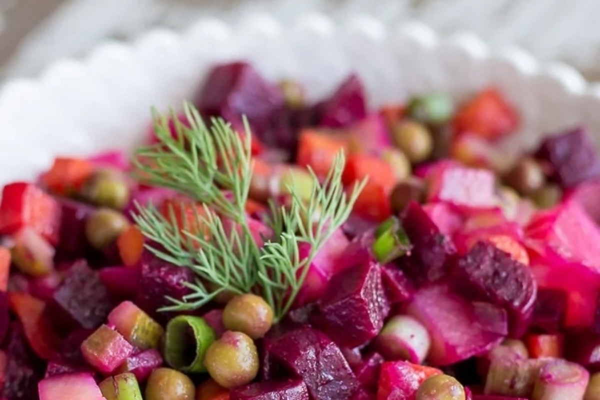 A bowl of beet and pea salad with a sprig of dill, perfect for those looking for delectable beet recipes.