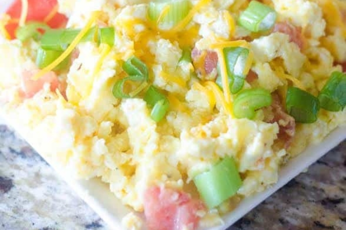 A healthy breakfast of scrambled eggs with tomatoes and onions, packed with high protein.