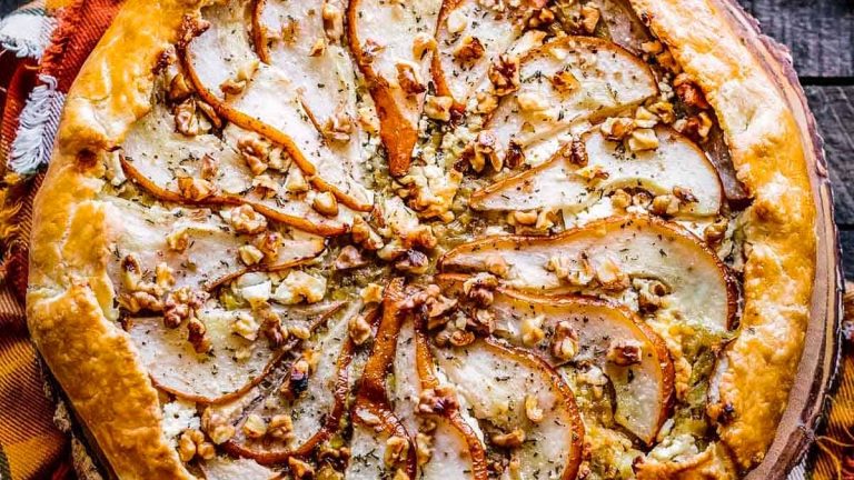 A goat cheese appetizer pie topped with pears and walnuts.