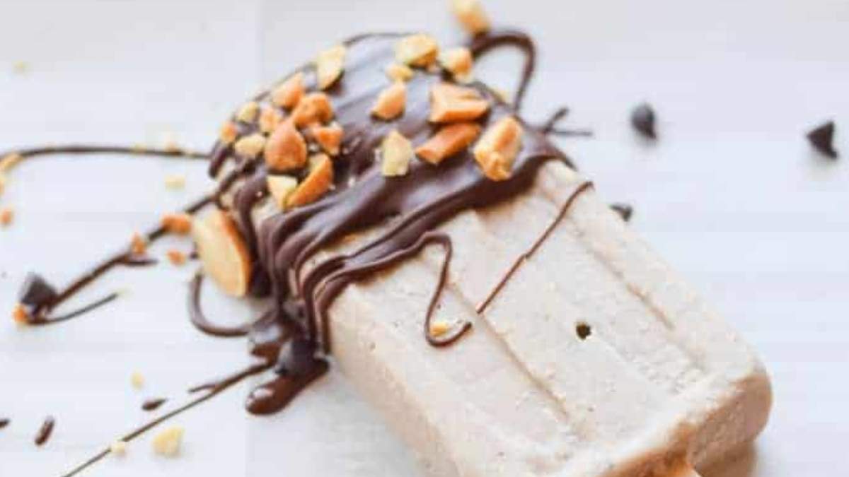 A shared popsicle topped with chocolate and nuts.