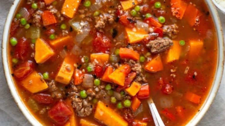 A bowl of stew with meat, vegetables and peas.