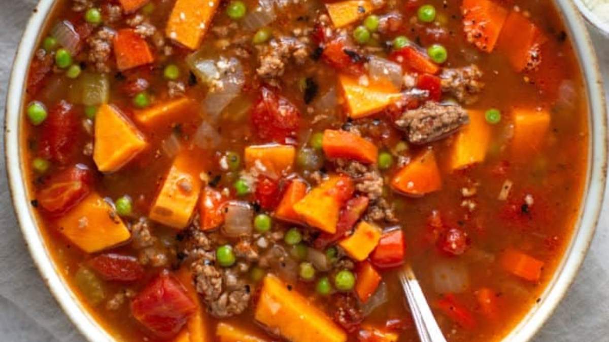 A bowl of stew with meat, vegetables and peas.