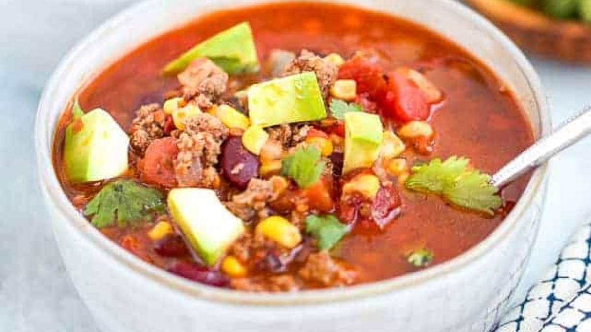 A bowl of chili soup in a white bowl.