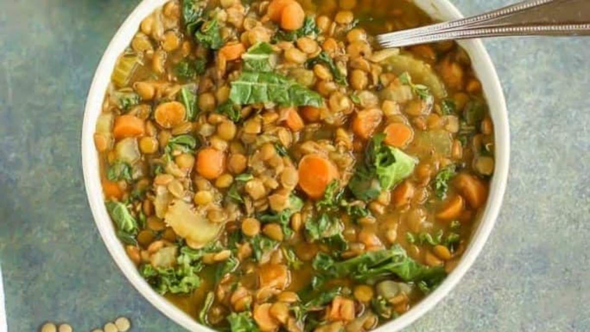 A bowl of lentil and kale soup with a spoon.