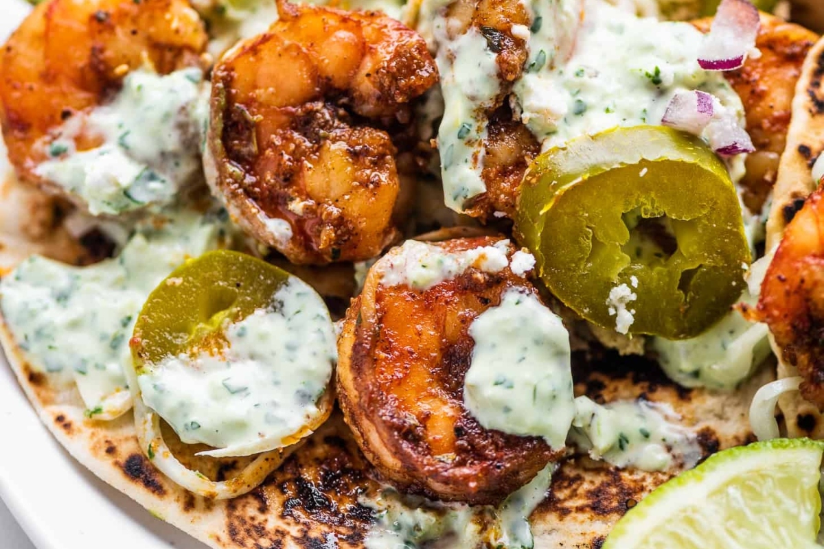 Shrimp taco dinner with guacamole and lime on a plate.