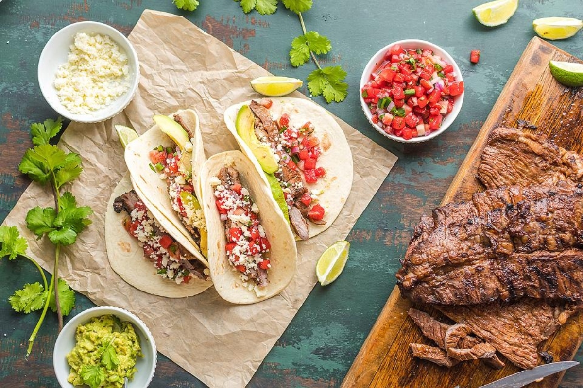 Taco night dinners with Mexican tacos beautifully presented on a wooden cutting board.
