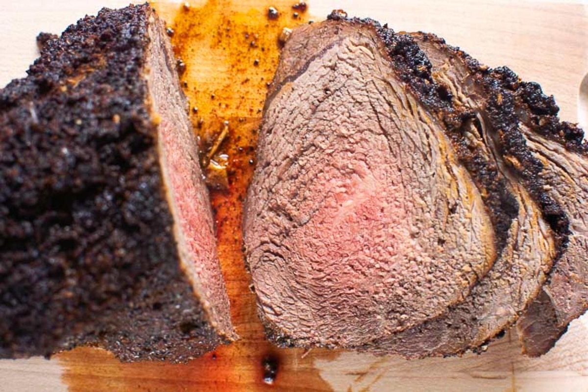 A piece of beef is cut in half on a cutting board, ready to be served for dinner.