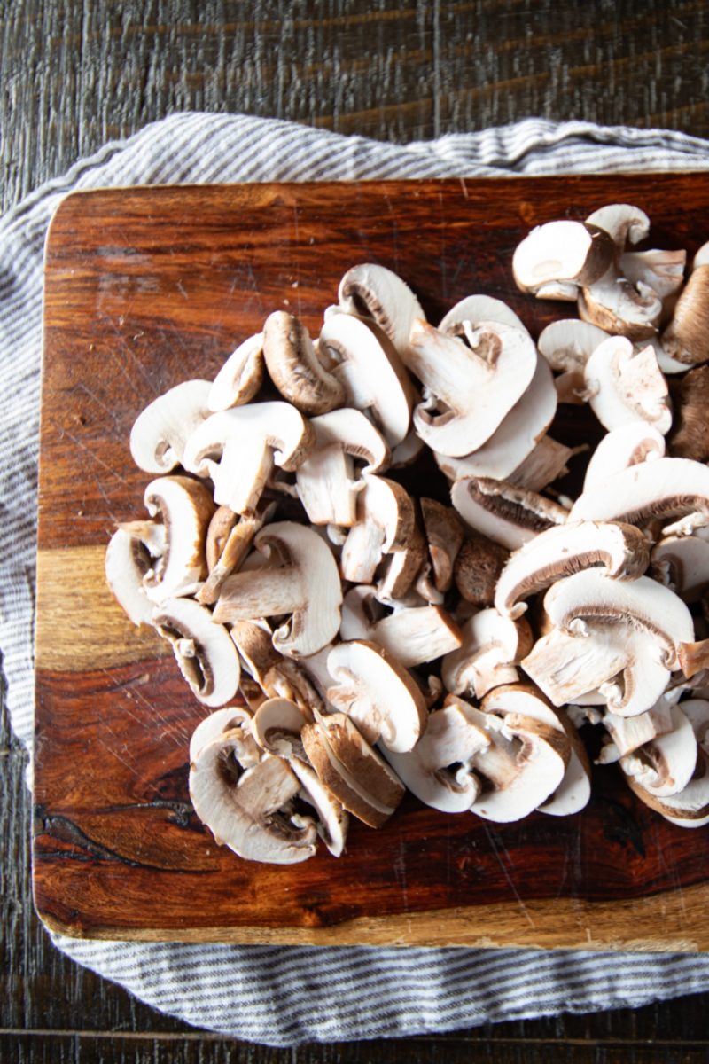 A wooden cutting board with air fryer mushrooms on it.